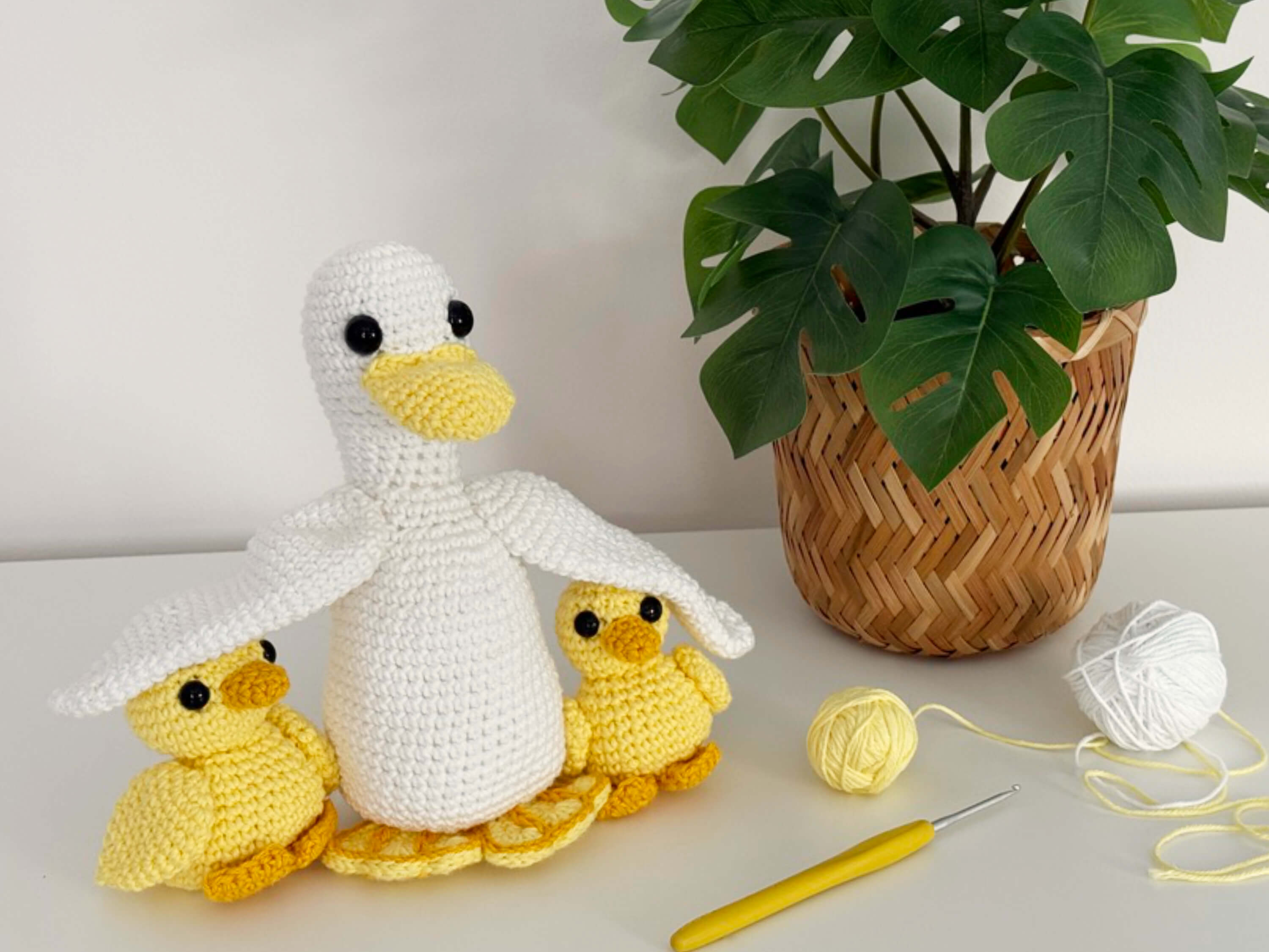 A white crochet duck with two smaller yellow crochet ducklings
