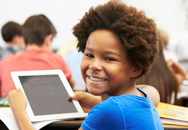 photo: young girl with afro looking over shoulder and smiling while holding a tablet