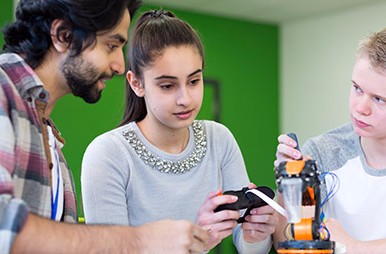 high-school boy and girl working on robotics project with male instructor
