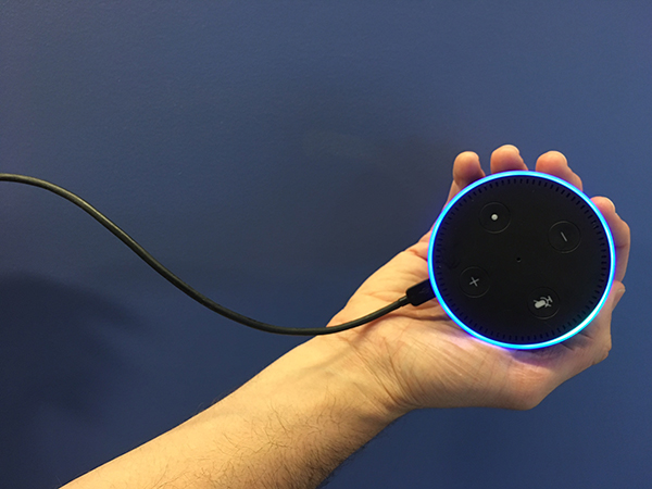 A hand holding the Amazon Echo Dot (Alexa).