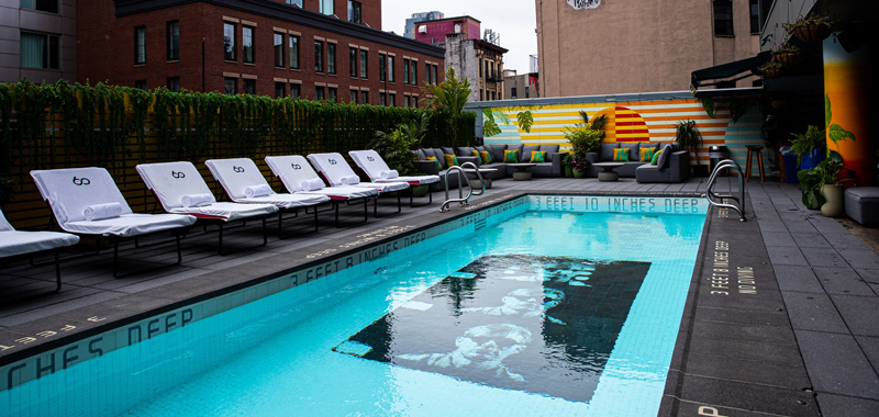 A pool with lounge chairs and a mural in the background