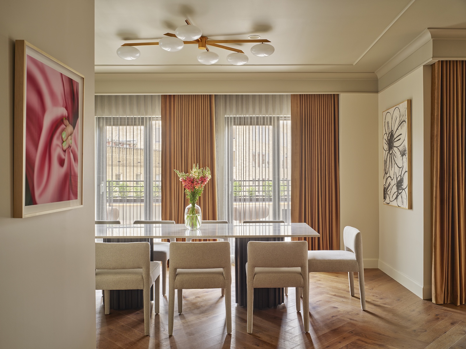 A dining area with a table, chairs, and artwork on the walls.