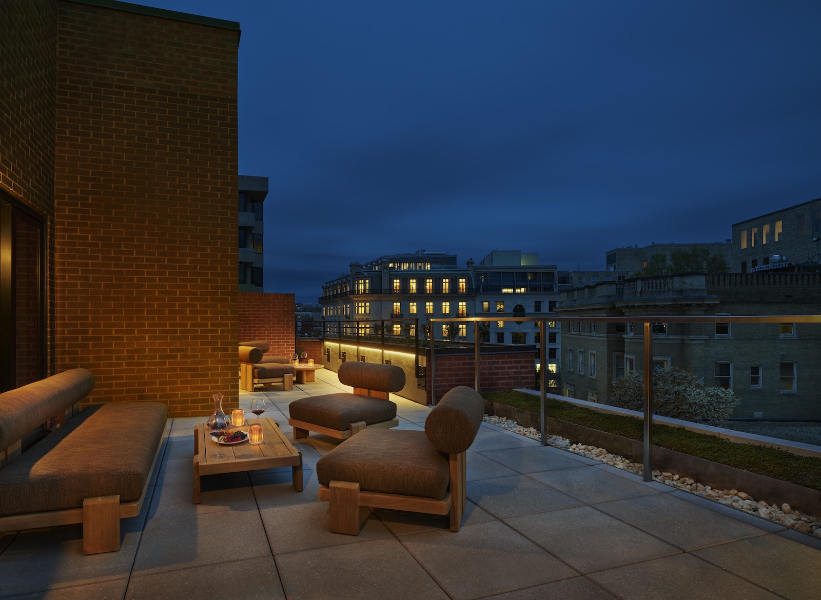 A rooftop patio with outdoor seating and a city view at dusk.
