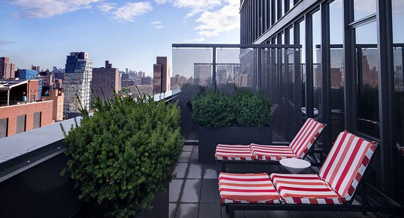 A rooftop patio with lounge chairs and a city view