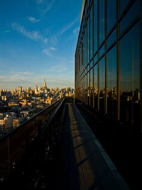 A rooftop view of a building with a glass facade overlooking a cityscape