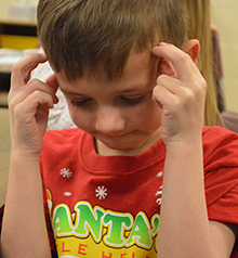Kindergartner Visser uses his thinking cap while coming up with words to describe his teacher