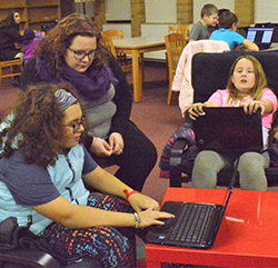 Sixth-graders Kyla Robinson (left) and Natalie Trader work on the computer app with help from robotics coach Meghan Bartoszek
