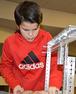 Sixth-grader Cole French checks a connection during early stages of making a team robot