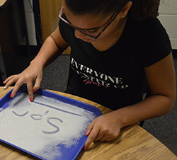 Southeast Kelloggsville Elementary School fourth-grader Aubrianna Vernon uses different methods to learn consonant blends, including writing in sand