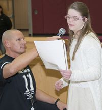 Owen Retan’s sister, Gracie, reads a letter praising her brother while event organizer Michael Lapciuk holds a microphone