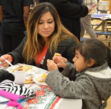 Janet Maldonado and first-grader Emily Amador eat at the Las Posadas feast