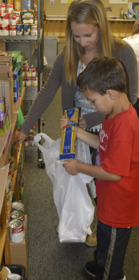 Laura Inman and her son, Micah, a Meadow Ridge student, fill a bag with weekend meals for a student