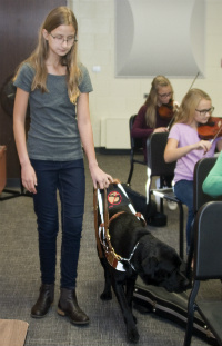 Julia enters orchestra rehearsal with her dog Duncan