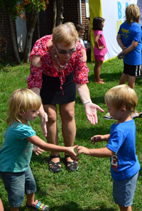 Assistant Superintendent JoAnn Spry dances to pop music with children during the Cedar Springs Mobile Estates back-to-school kickoff