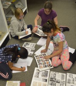 Kent City fifth-graders amid yearbooks and newspaper clippings on the historical society floor