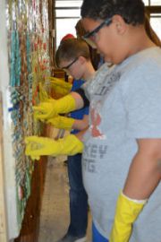 Third-grader Taychaun Donald works to clean grout from mural tiles