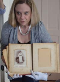 Lowell Area Historical Museum Director Lisa Plank shows students an antique photo album donated by a local family