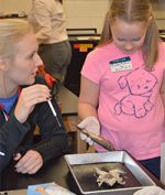 Senior Paige VanderWall shows fifth-grader Vivian Kolkman a frog and fish dissection