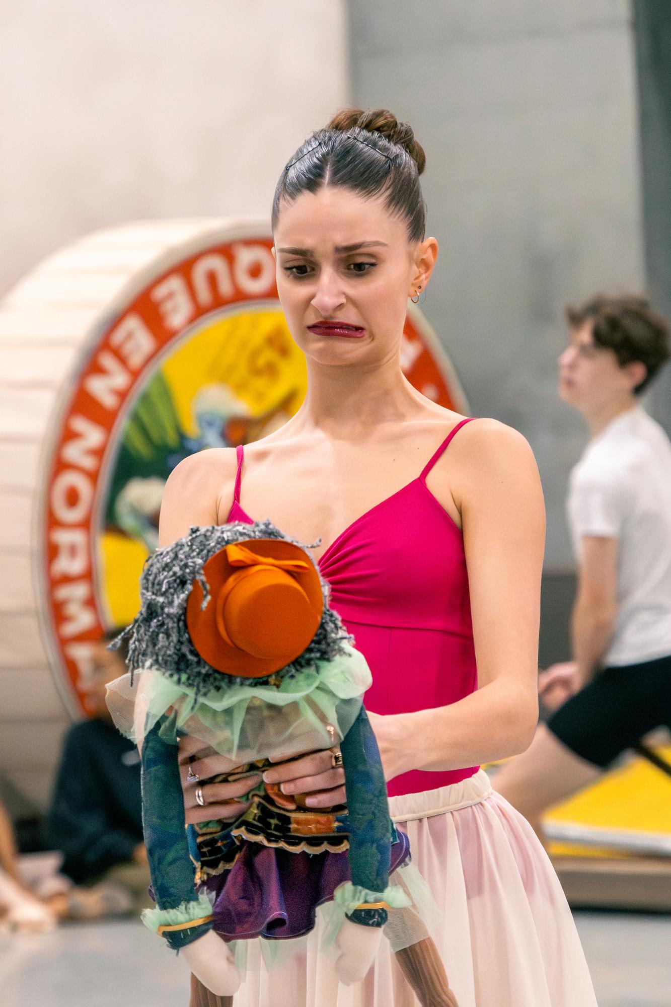 A ballerina makes a silly face at a blue nutcracker doll