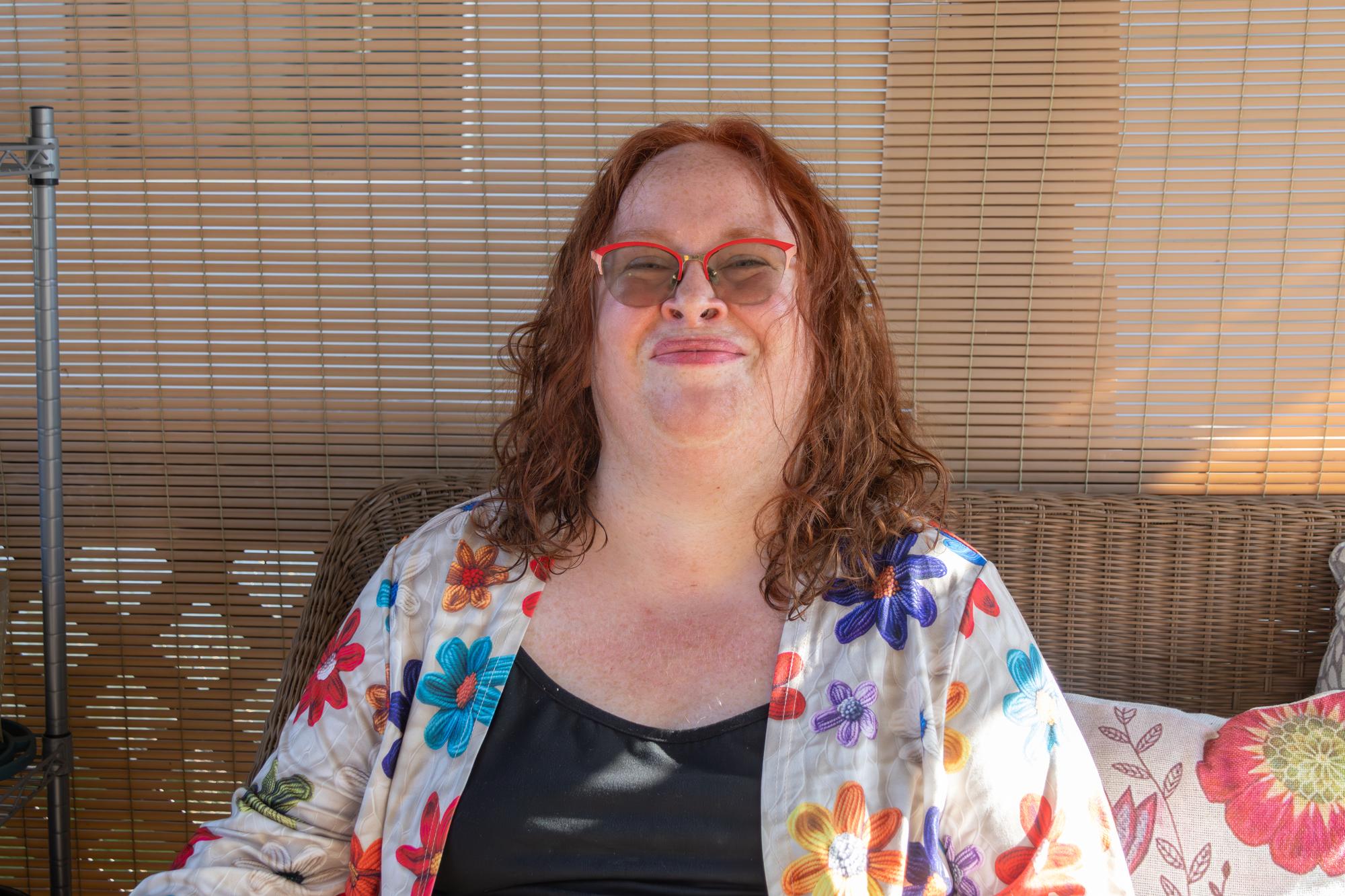 Headshot of a person wearing a flower print blouse and glasses.