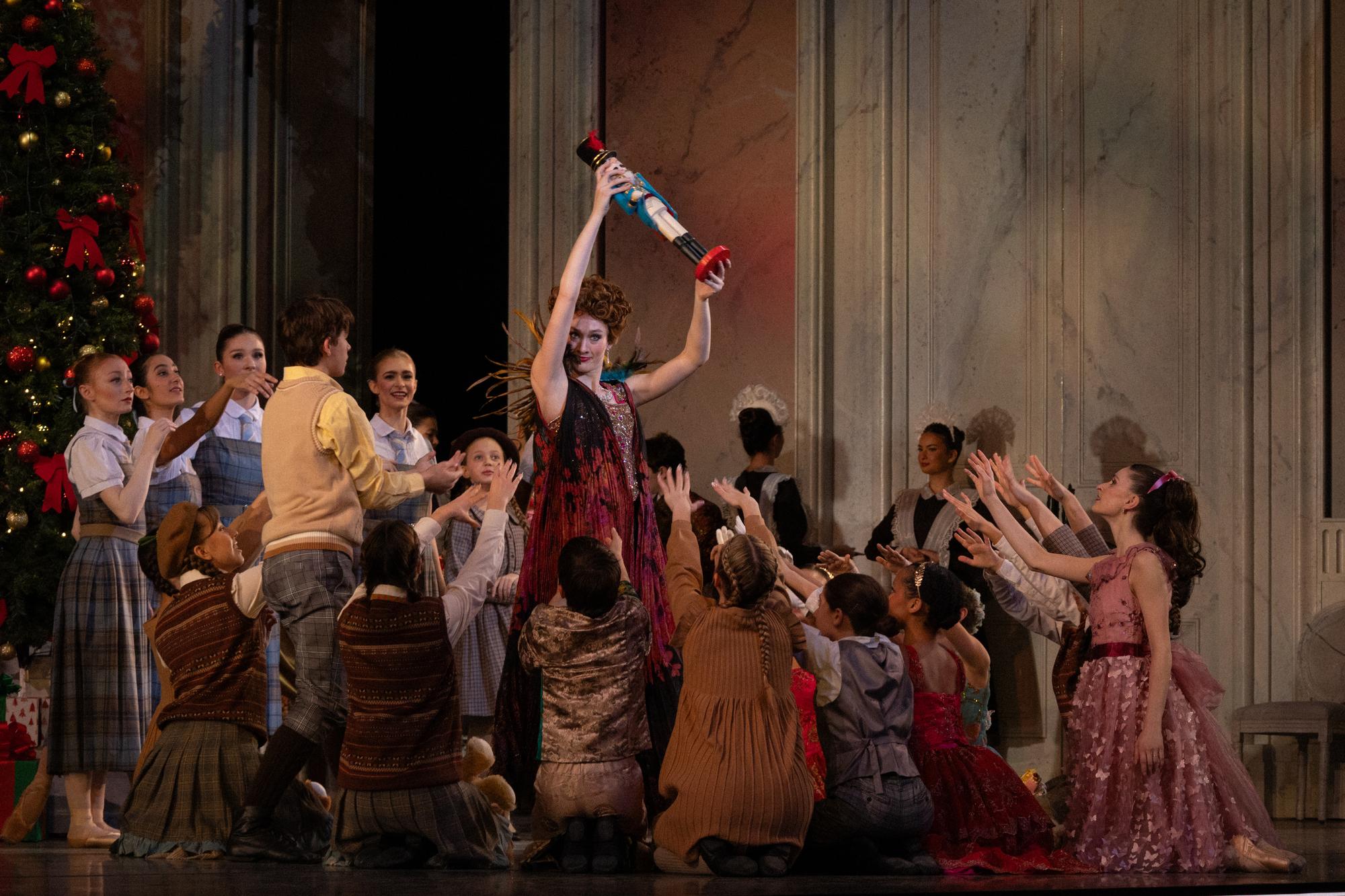 Drosselmeier holds a doll above the heads of a throng of children