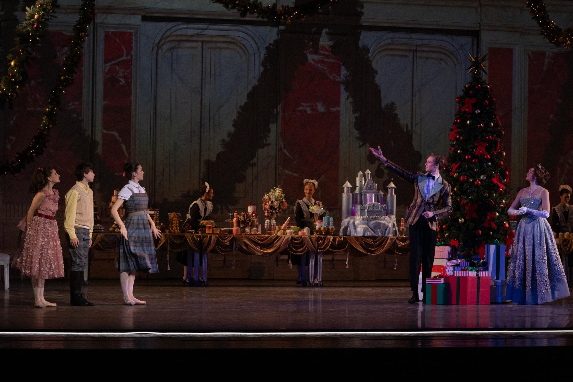A dancer on the right raises his hand welcoming guests to the party on stage