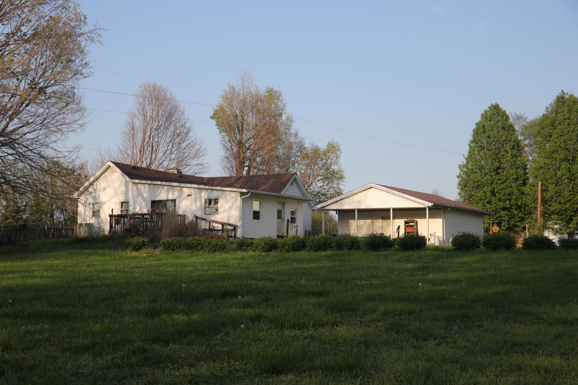 A white home surrounded by trees and bushes.