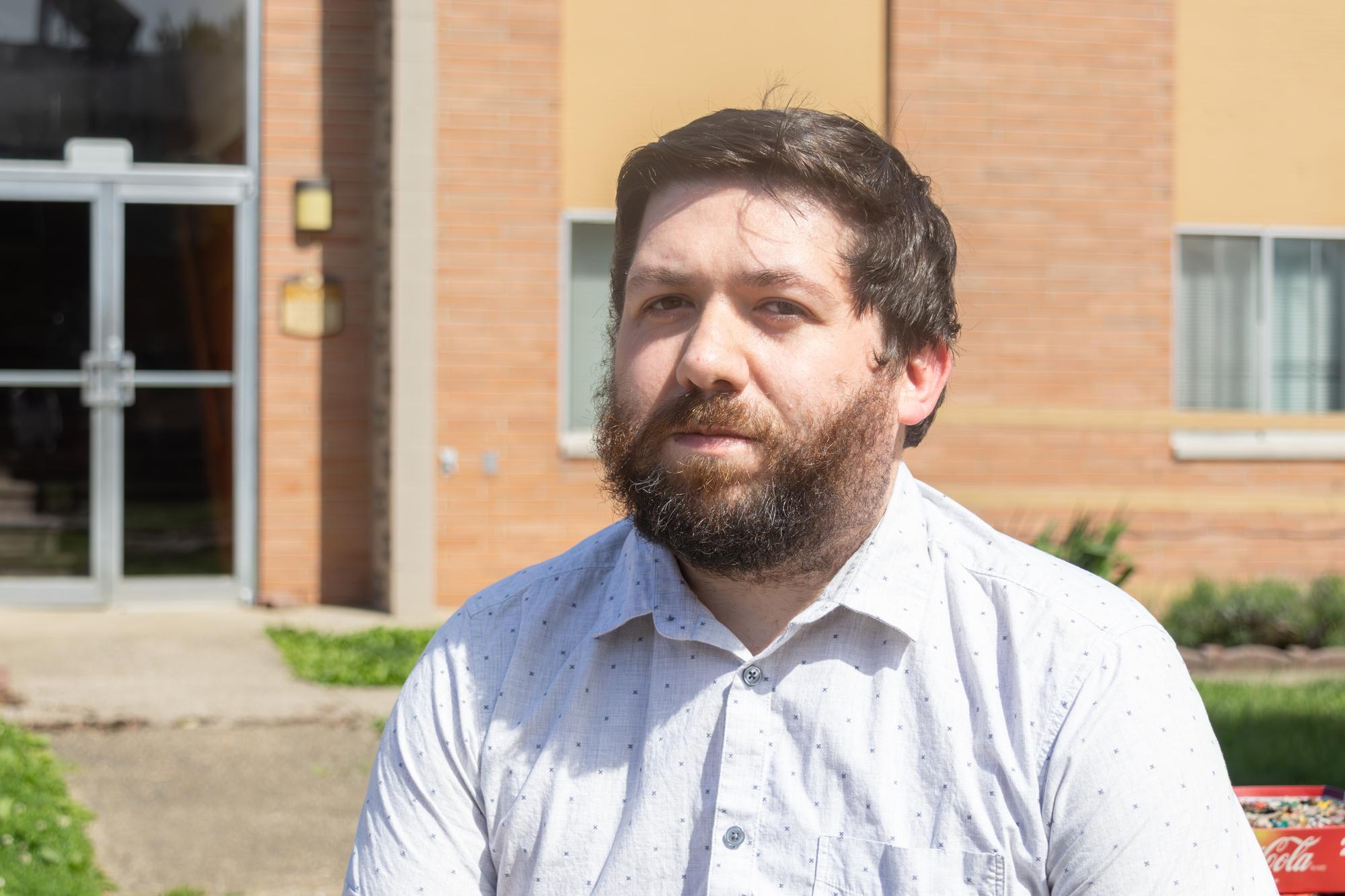 A bearded man in a white button down shirt.