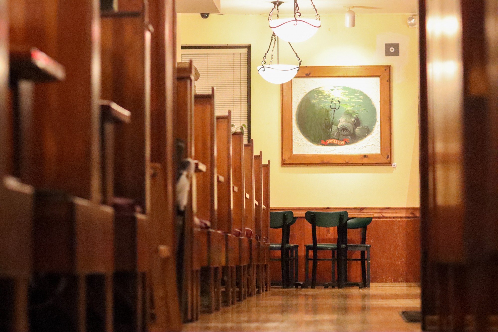 A row of wooden booths lead to the back wall of the restaurant, which is decorated with artwork depicting Poseiden.