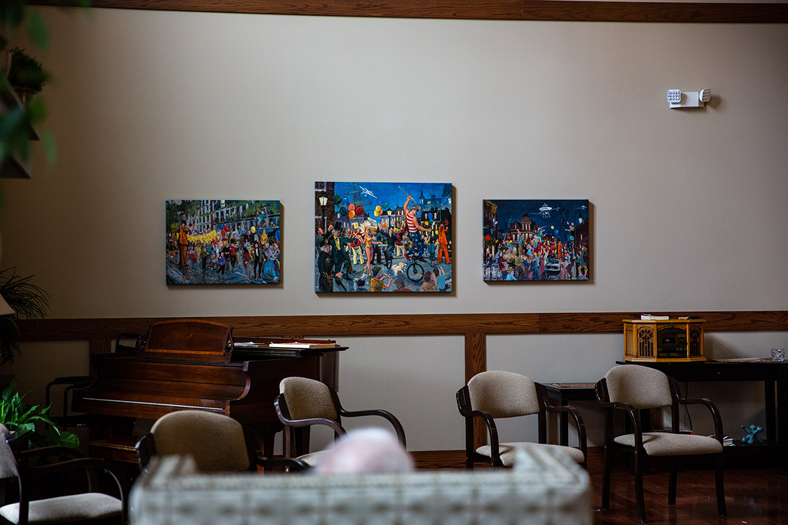 Jim sits in front of his paintings.