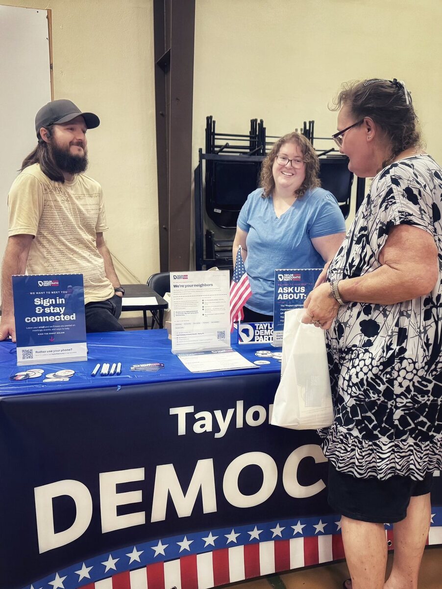 Taylor County Democrats volunteers welcoming a neighbor at a community table