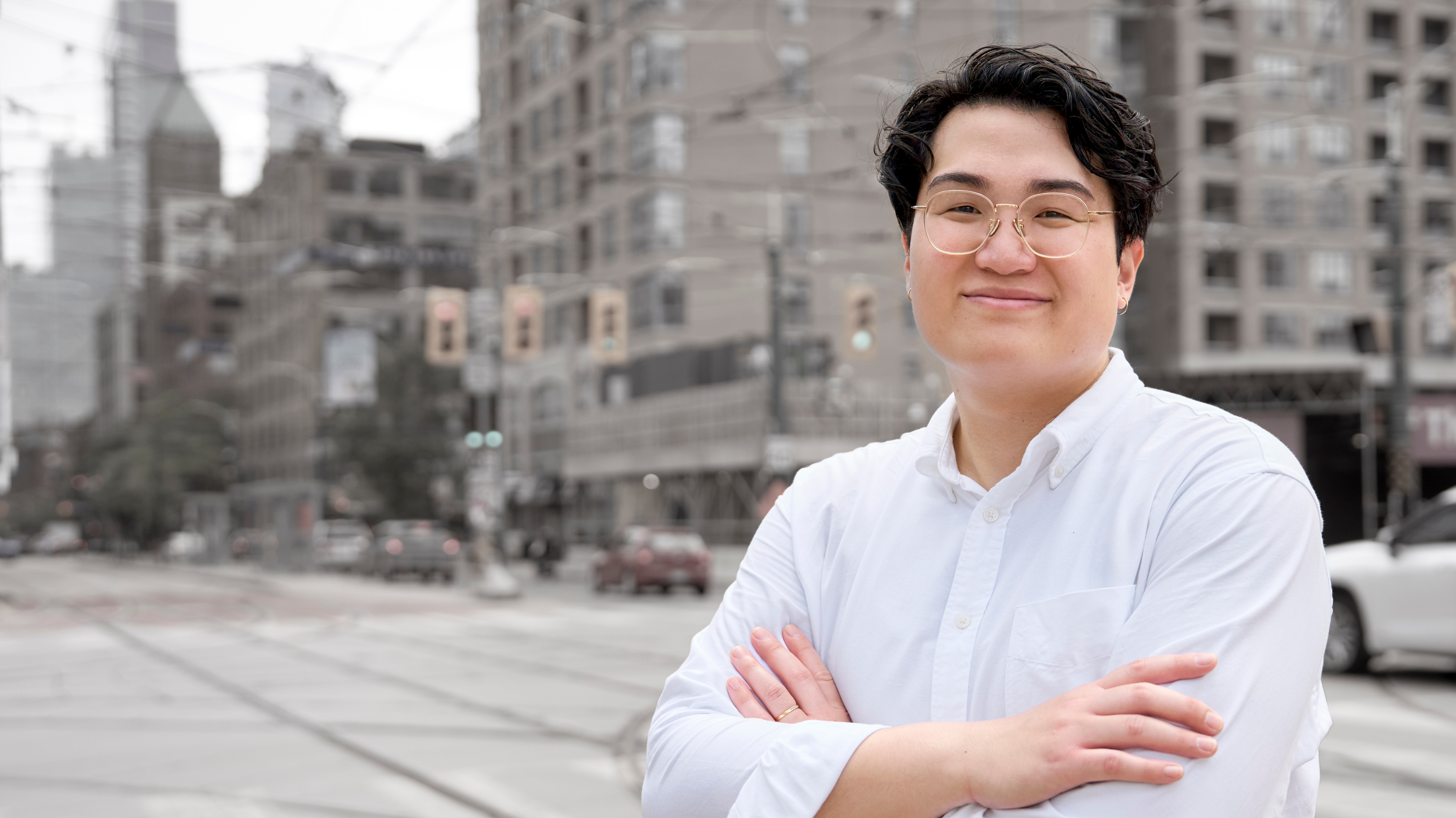 A photo of Andi, a non-binary Vietnamese person, standing at a city intersection
