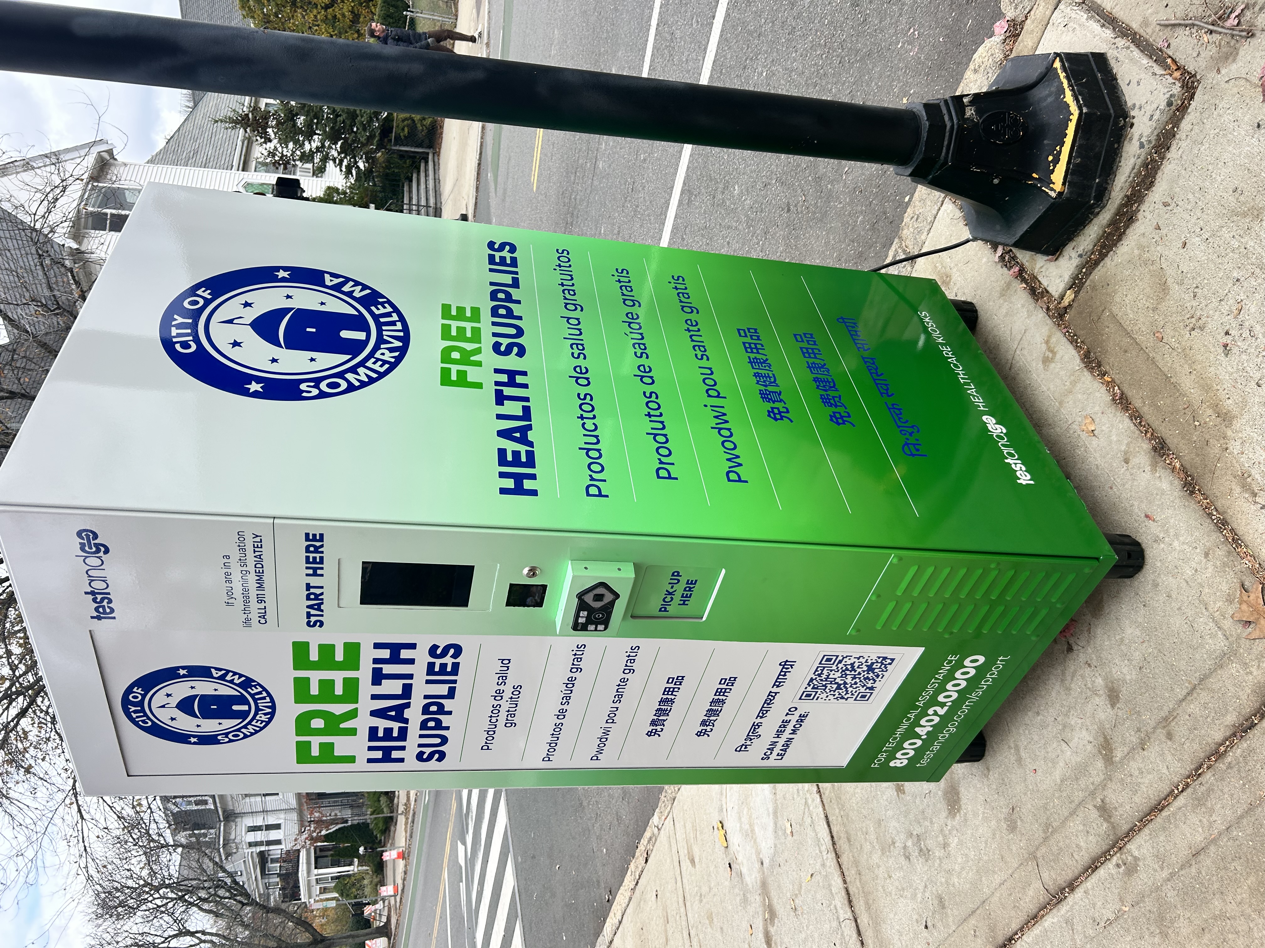 Green and white health kiosk with "free health supplies" on the side and the Somerville city seal. 
