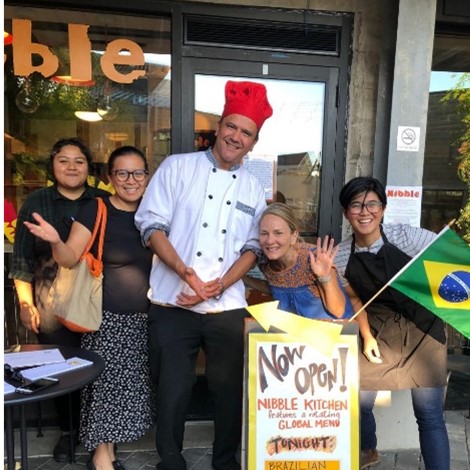 A chef and group of patrons outside a Somerville restaurant smiling for the camera. 