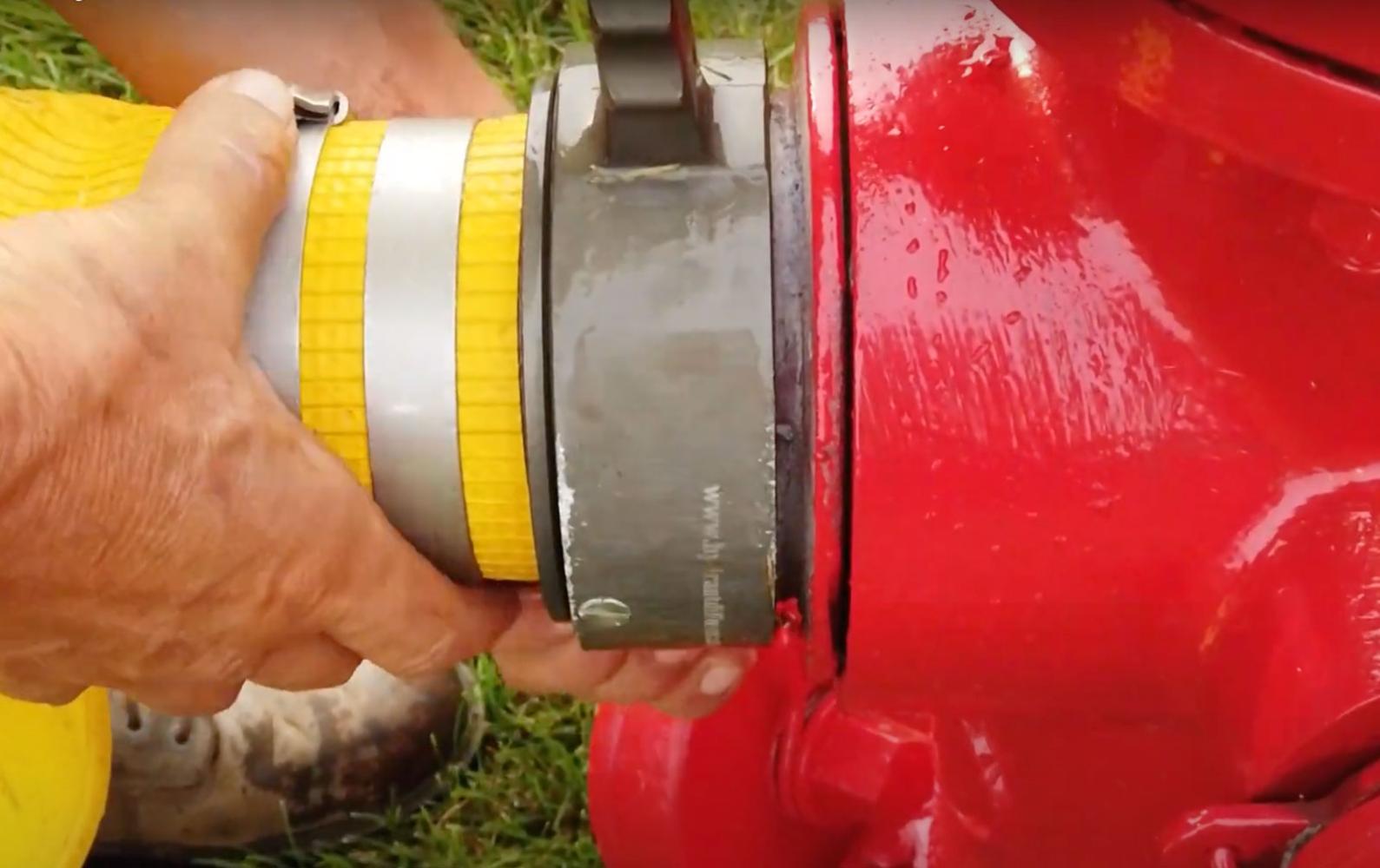 Worker connecting fire hose to the side of a fire hydrant
