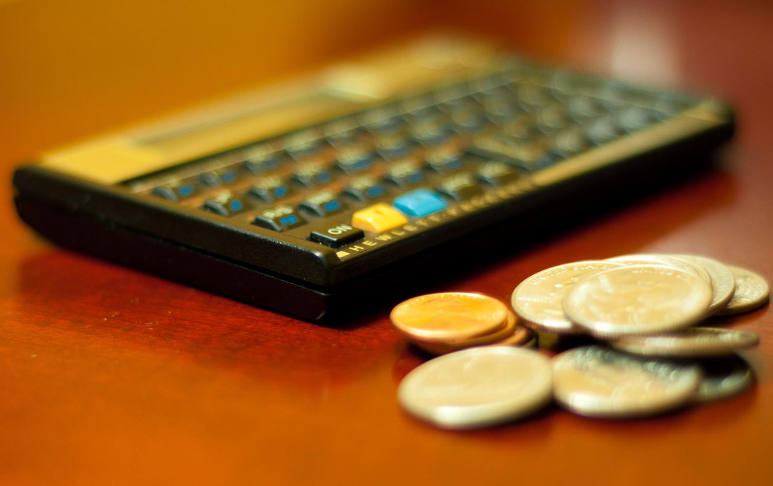 HP 12C calculator alongside a stack of coins