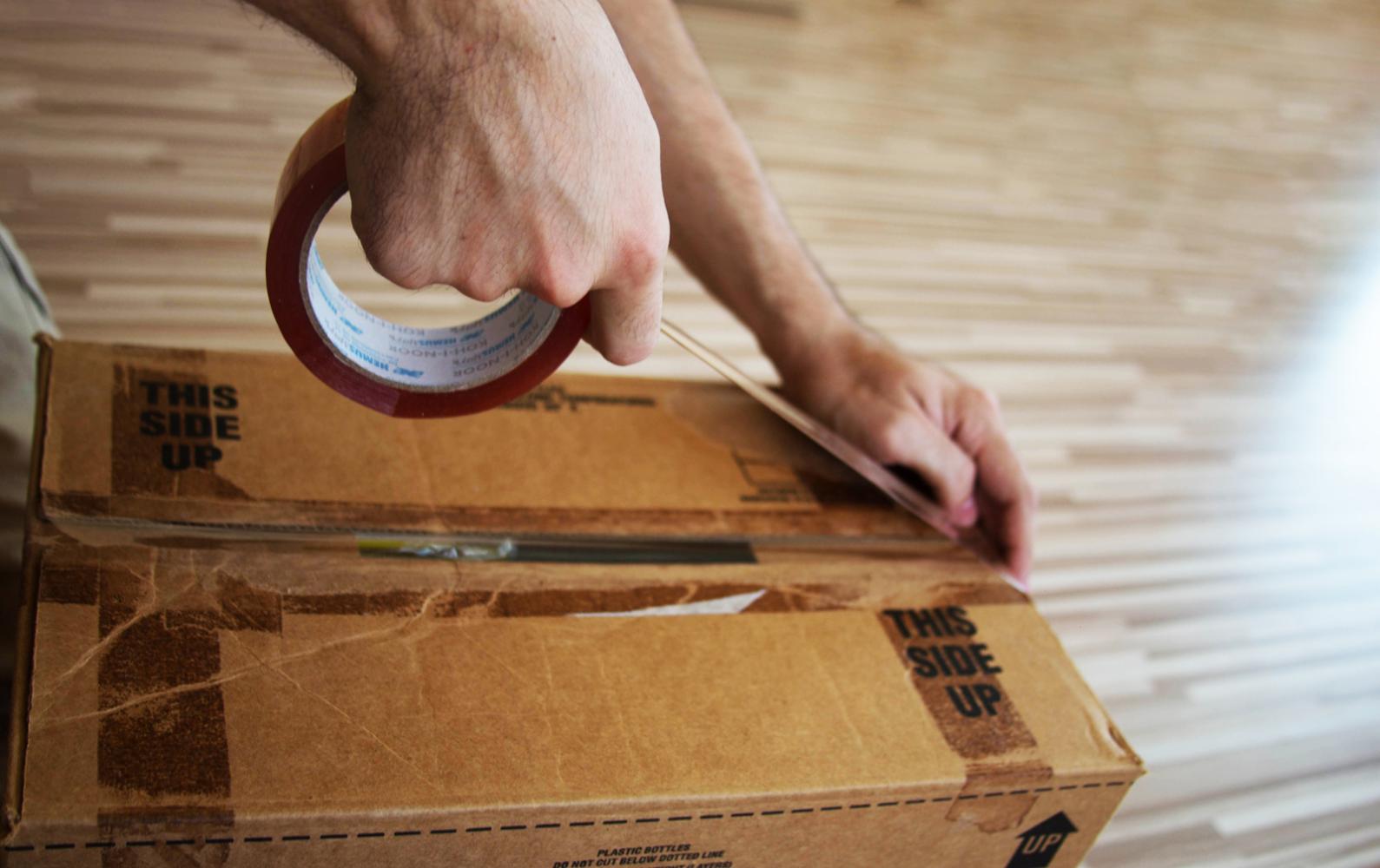 Person closing a box with packing tape