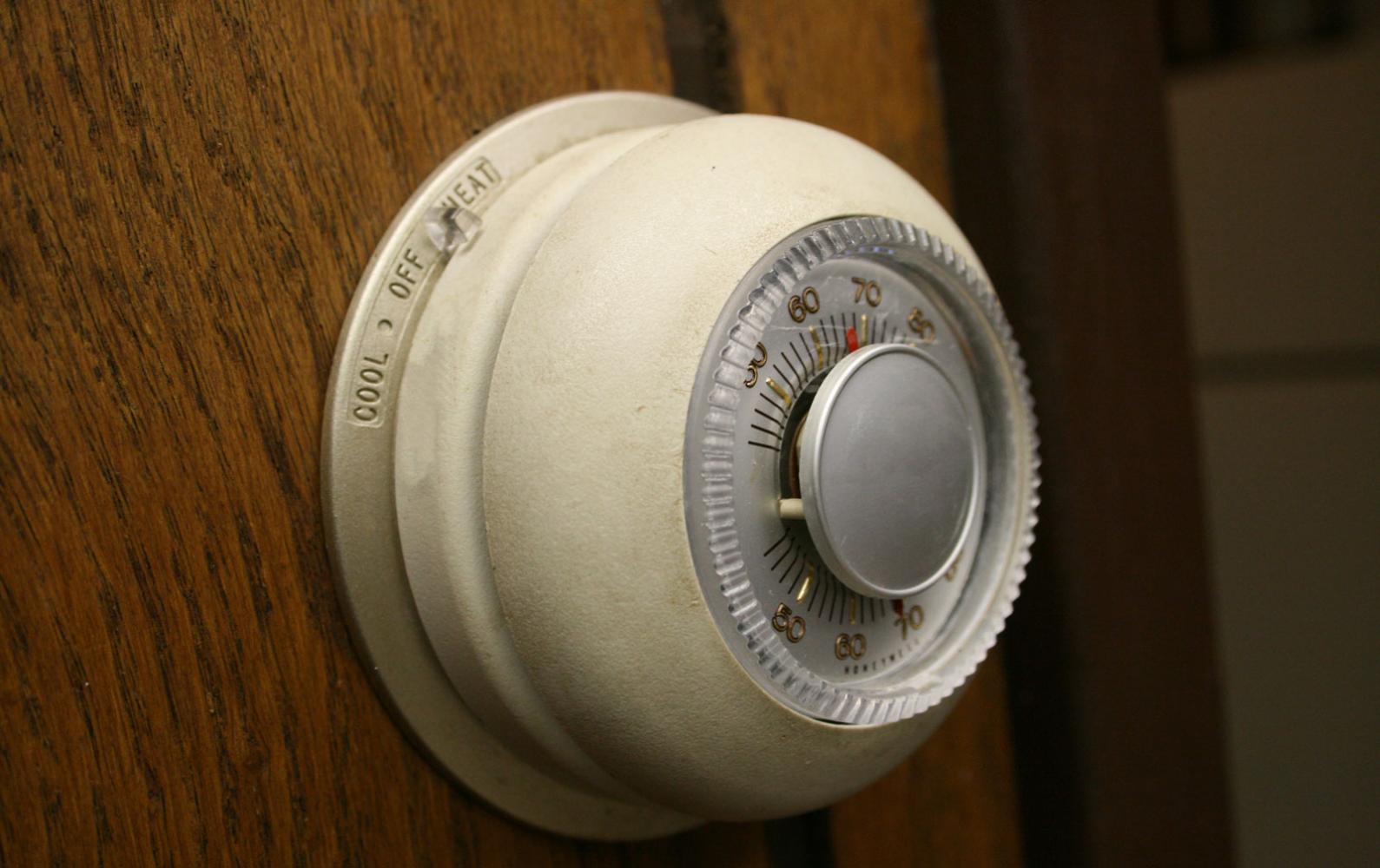 An analog dial thermostat in a home set to 68F