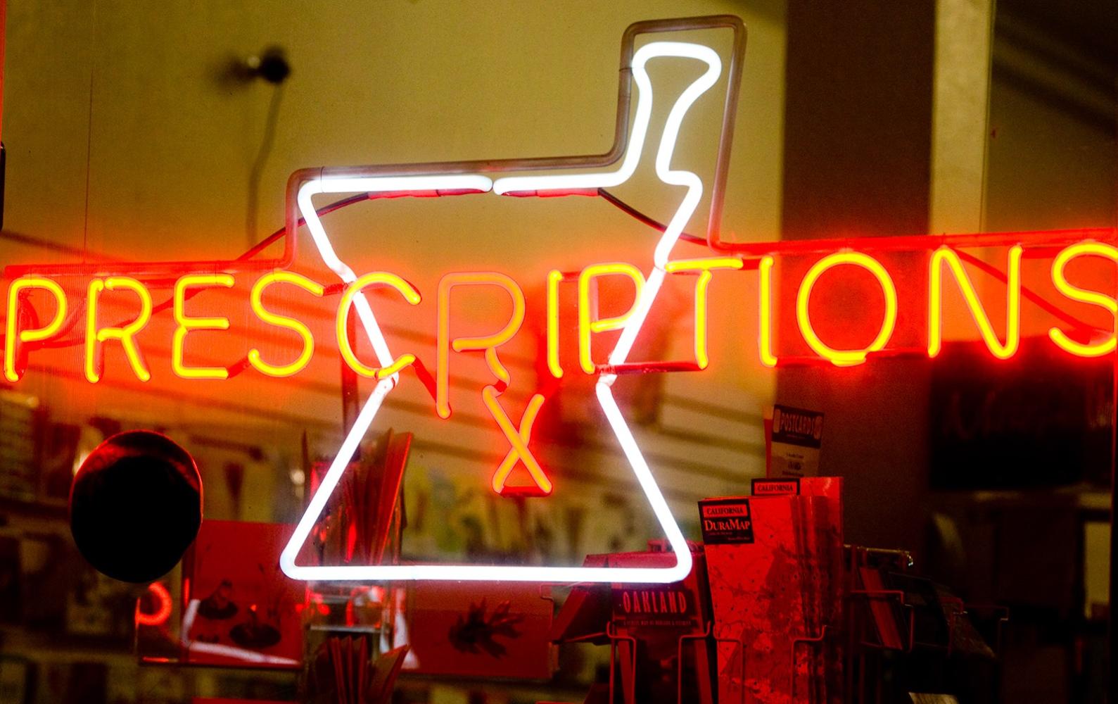 Neon sign reading "Prescriptions" in storefront