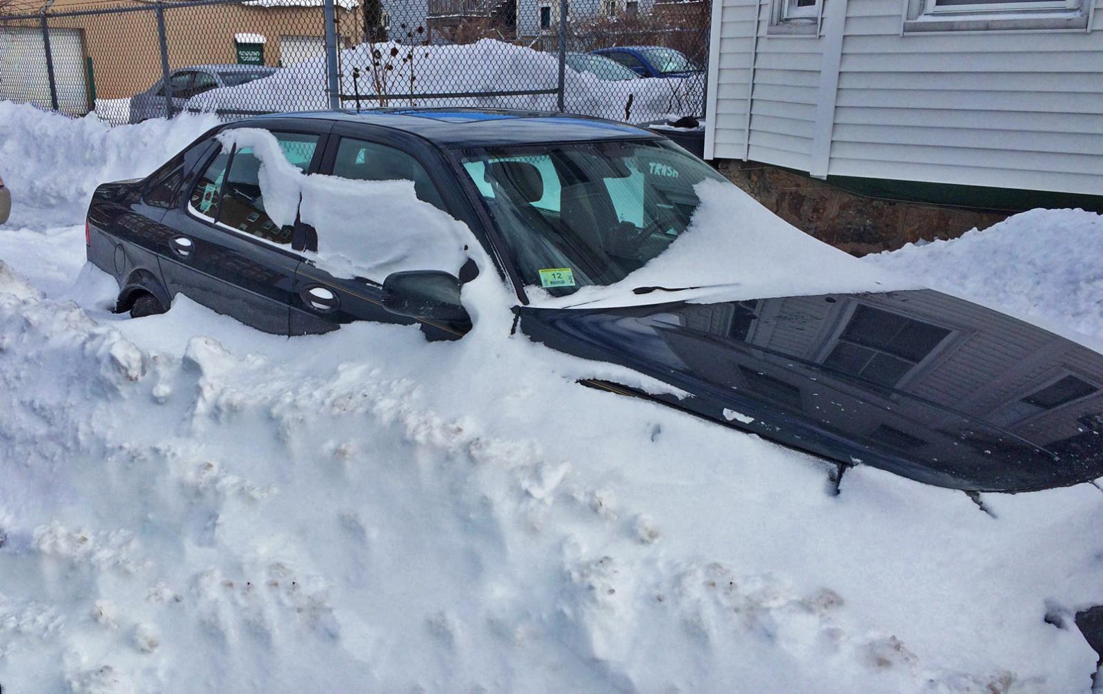 A green Saab is just barely visible beneath a snow drift.