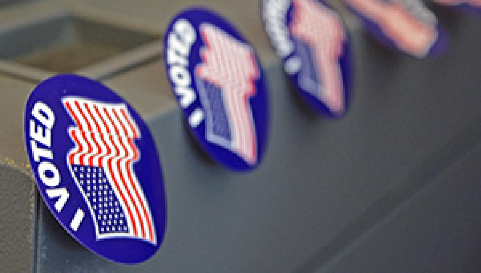A row of 'I Voted' stickers affixed to the corner of a voting machine