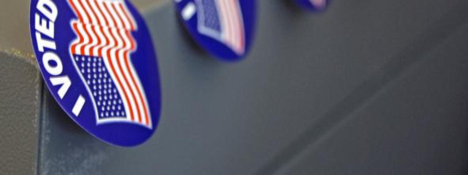 A row of 'I Voted' stickers affixed to the corner of a voting machine