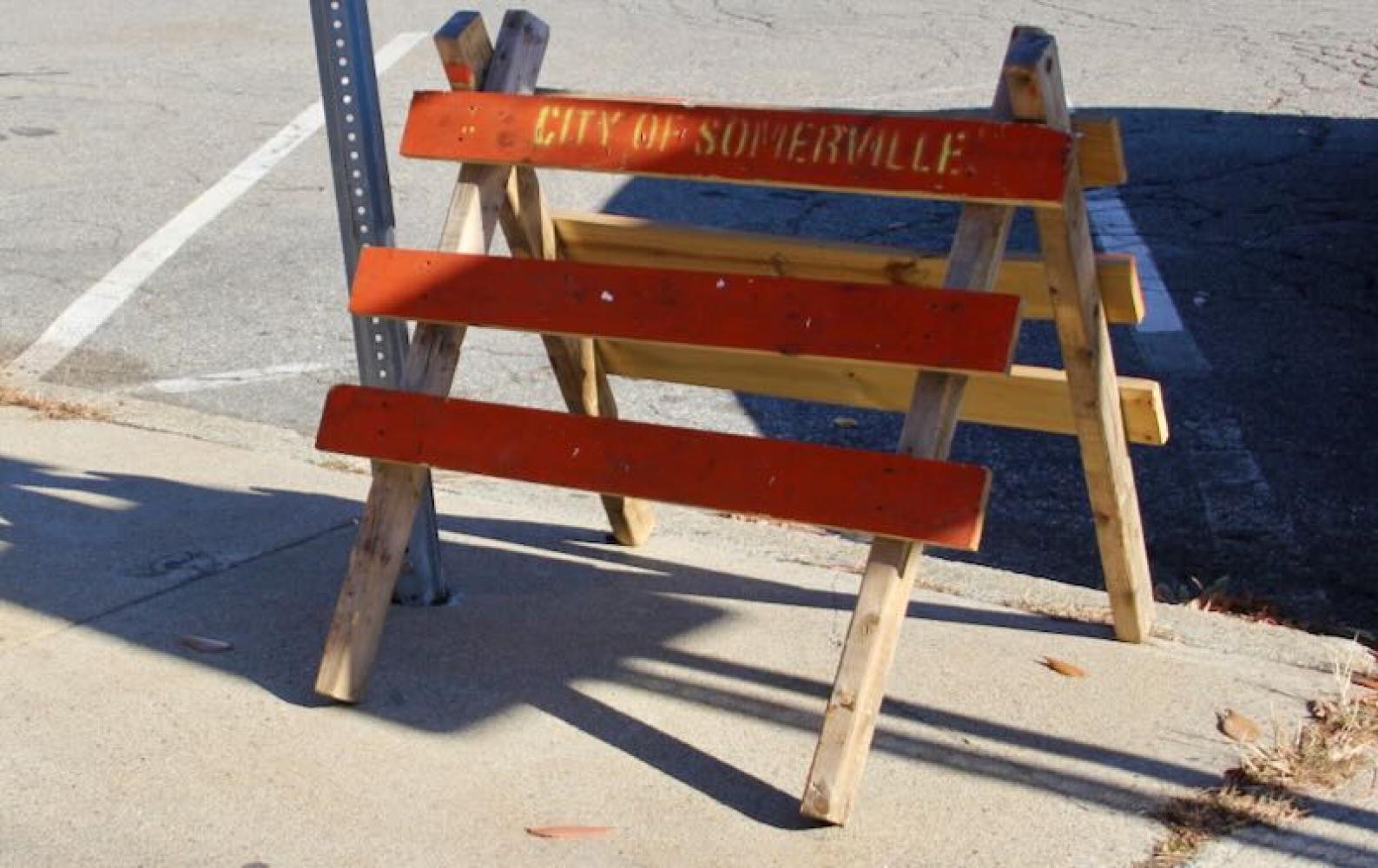 Close up of an orange wooden sawhorse reading: City of Somerville.