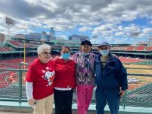 Four people posing at Fenway Park at a Council on Aging event there. 