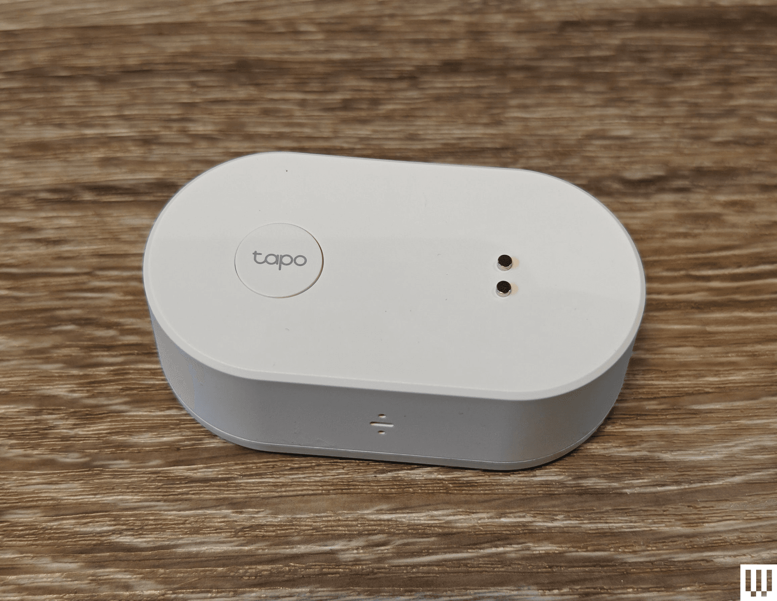White oval shaped device sitting on wooden surface. Product is branded with the name Tapo.
