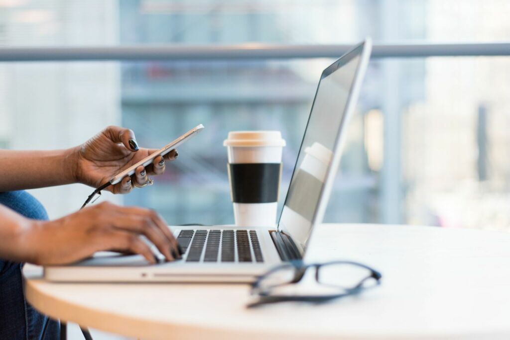 Hands working on a laptop on a coffee shop table