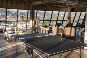 Photo of Ping Pong tables setup with city in background through windows