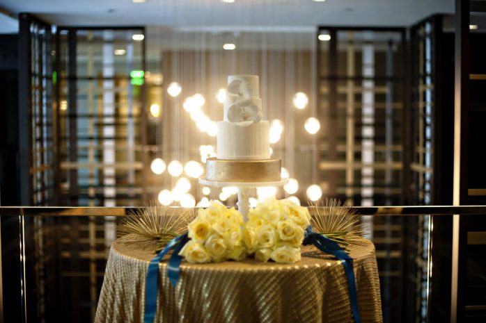 Photo of a wedding cake on a table backlit by art