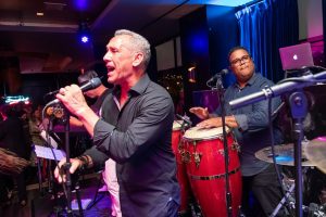 Photo of a singer onstage with drummer in background