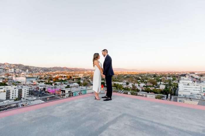 Photo of a couple on the helipad with the city sunset in the background